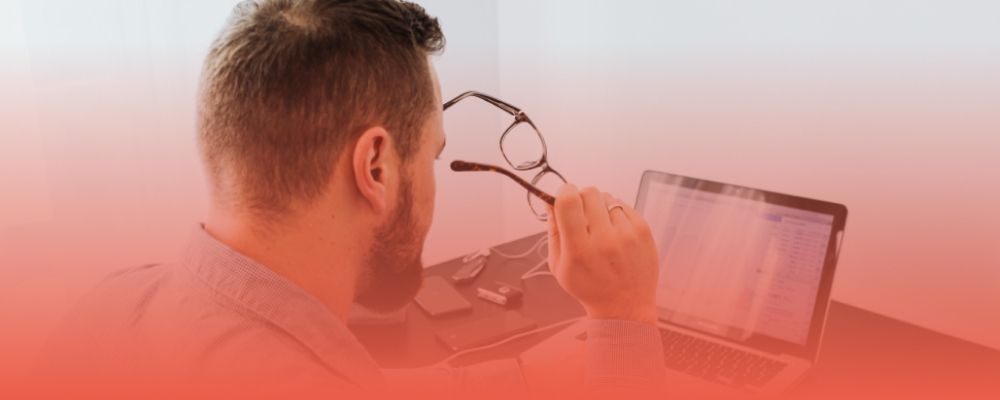 Developer reviewing information on a laptop while holding glasses, illustrating an evaluation of Open Mercato's pros and cons
