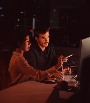 Businesswoman pointing on laptop while explaining to colleague in office