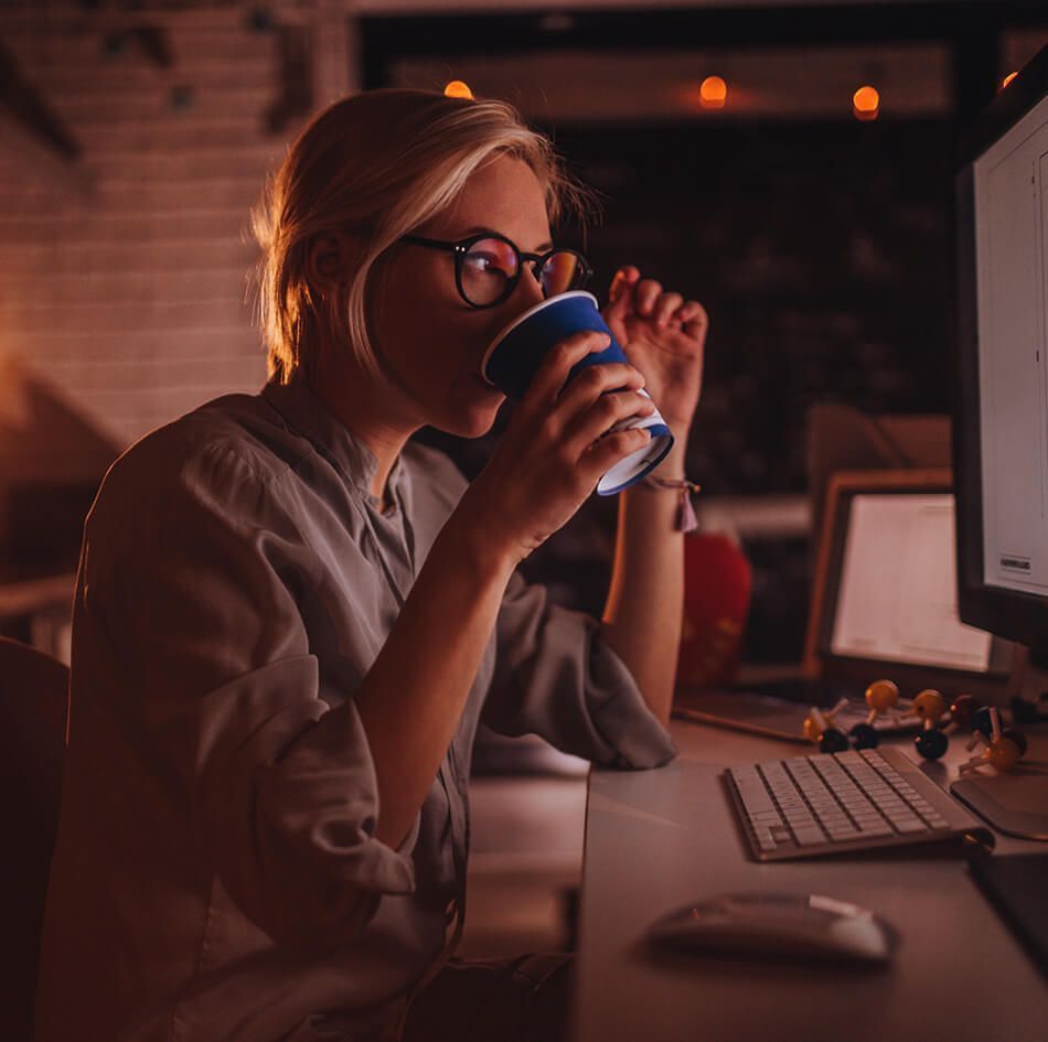 Woman working on computer while drinking coffee_image