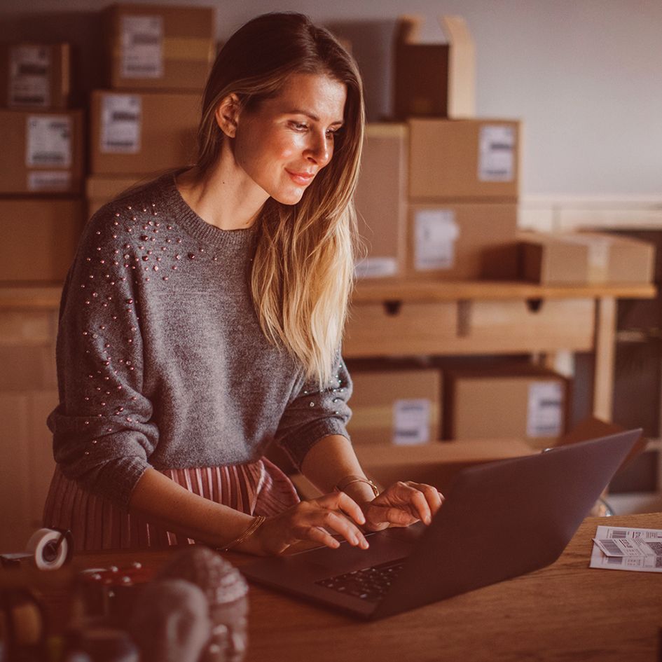 Business woman checking parcels and using laptop_image