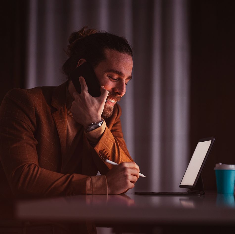 Man using mobile smartphone and holding a digital pencil in front of tablet_image