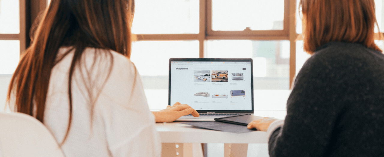 Two women talking while looking at laptop computer_image