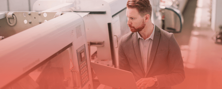 Manufacturing professional using a laptop on the factory floor, illustrating how headless CMS helps solve slow website performance issues for manufacturers.