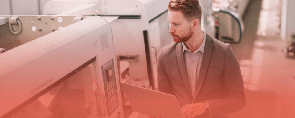 Manufacturing professional using a laptop on the factory floor, illustrating how headless CMS helps solve slow website performance issues for manufacturers.